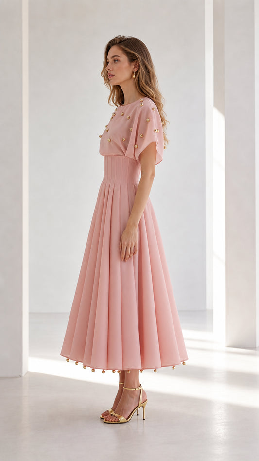 Side profile view of blush pink studded pleated midi dress