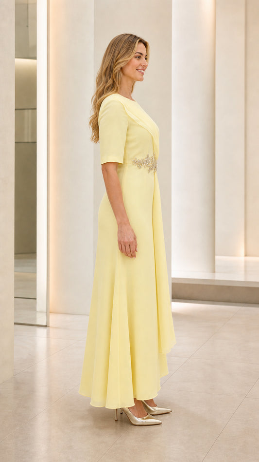 Side profile view of model in pastel yellow draped evening dress with side sash