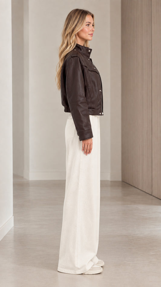 Side profile view of woman modeling the dark brown cropped faux leather jacket