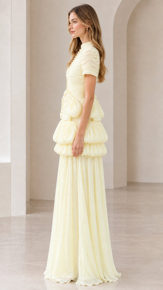Side profile of model wearing pale yellow short-sleeve pleated evening gown