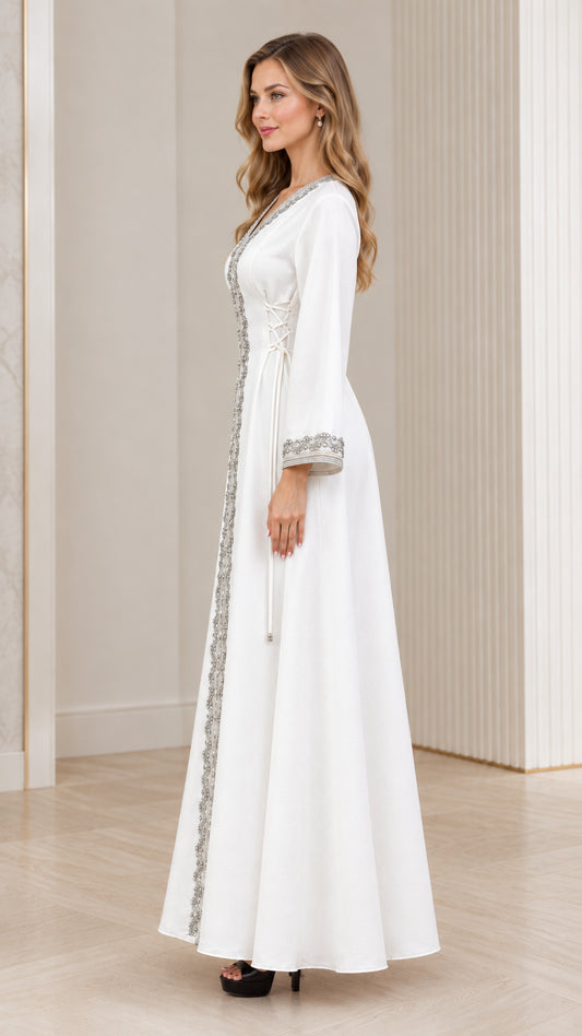 Side profile of woman wearing white embroidered full-length kaftan gown