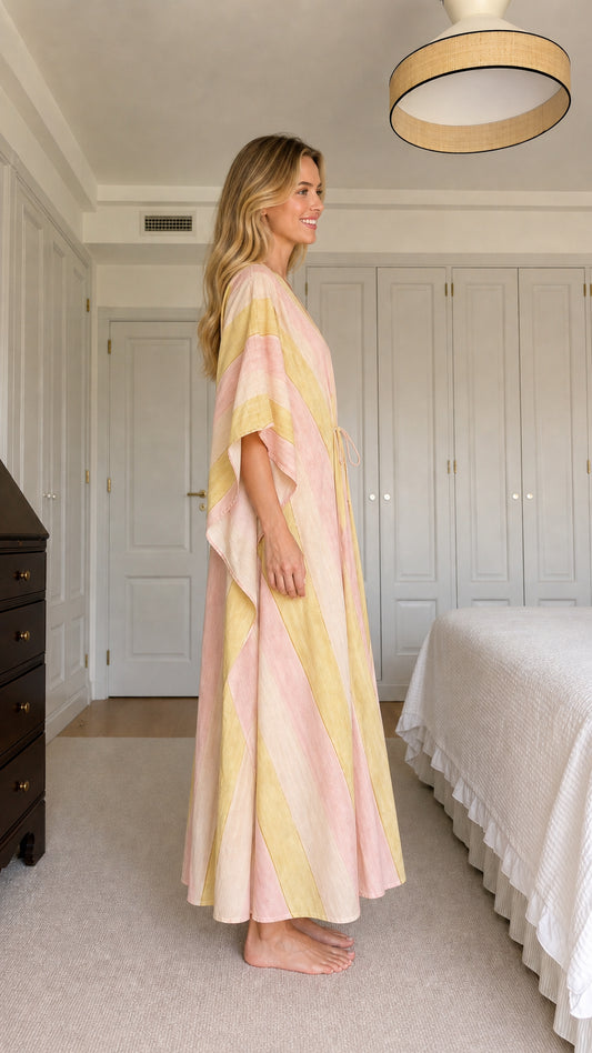Side view of model wearing pink and yellow striped maxi kaftan dress