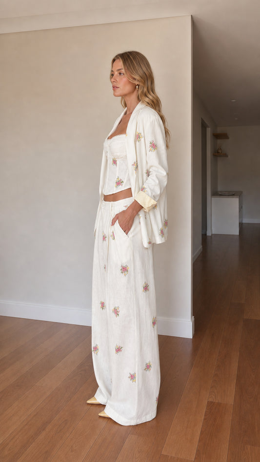 Side angle view of woman wearing cream embroidered 3-piece blazer and pant set