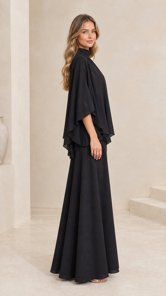 Side profile of woman in flowing black tiered cape maxi gown