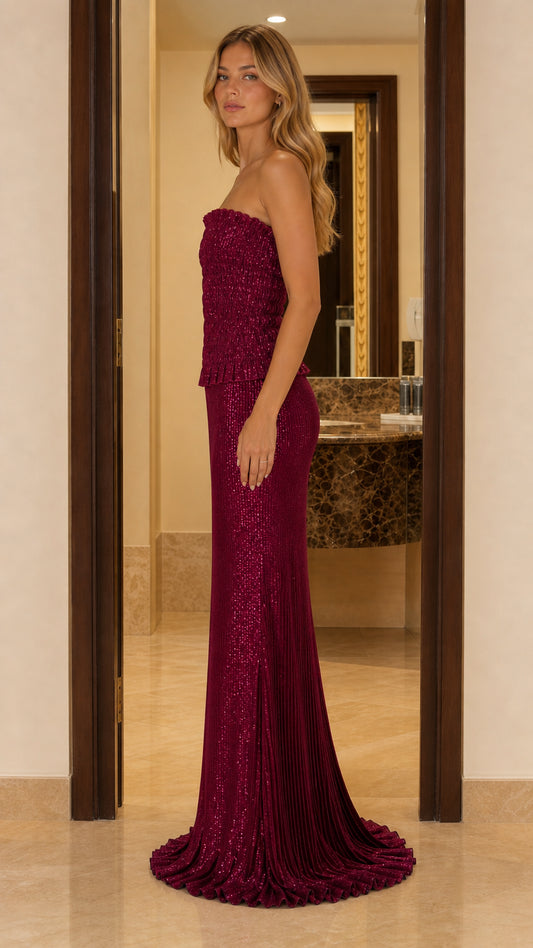 Side view of a burgundy strapless floor-length maxi dress with a softly flared train