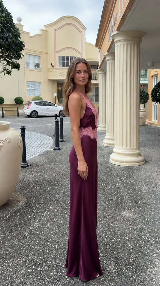 Side profile view of burgundy lace-trimmed halter satin maxi dress