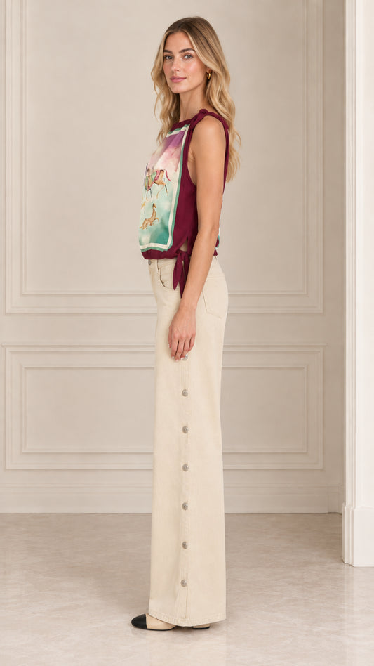 Side view of women's burgundy tie shoulder scarf top with beige trousers