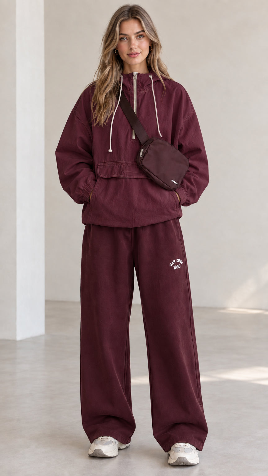 Full-length front view of model wearing burgundy half-zip hooded anorak jacket