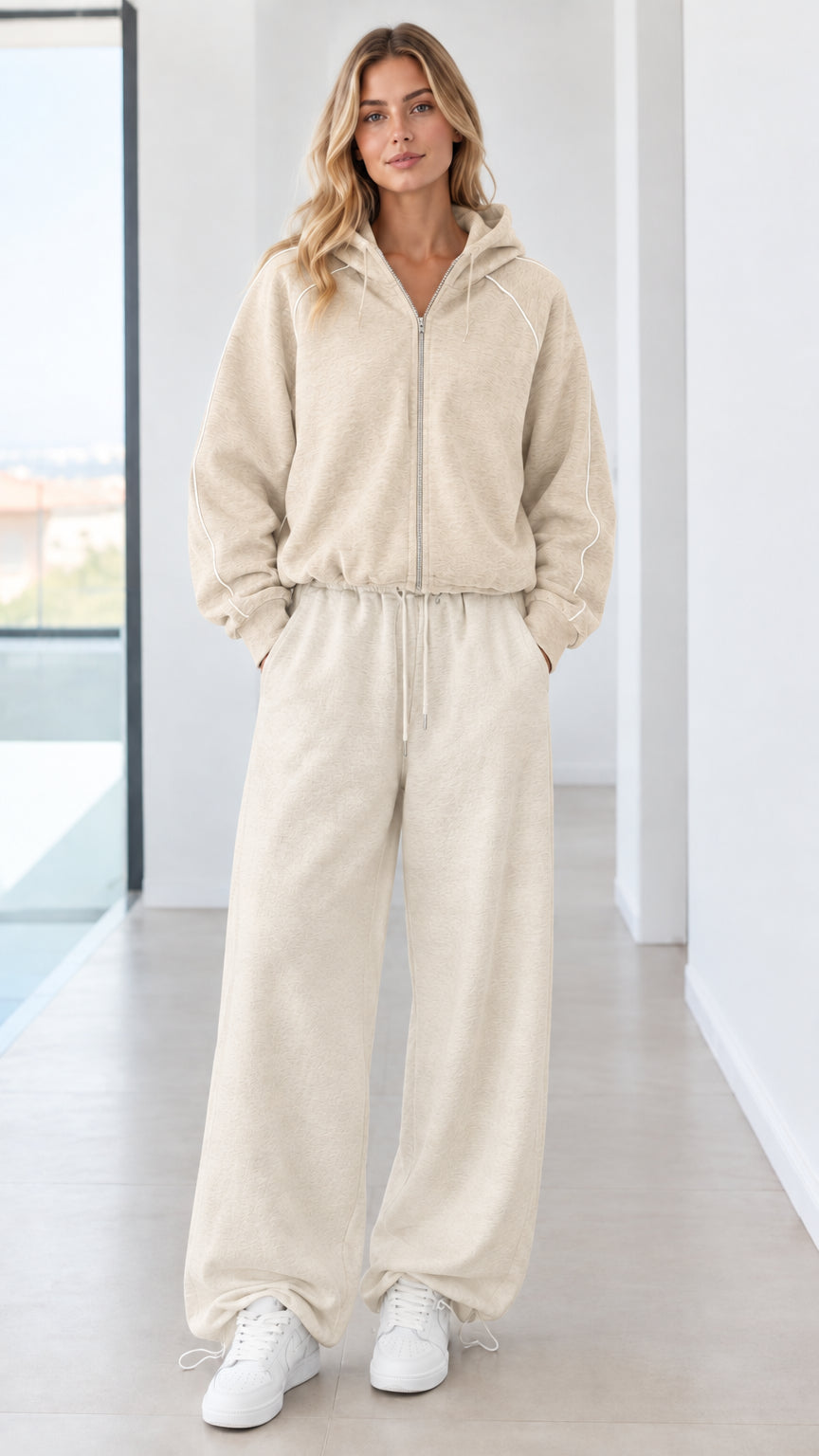 Full body studio shot of model wearing beige cream zip-up hoodie and wide-leg sweatpants set