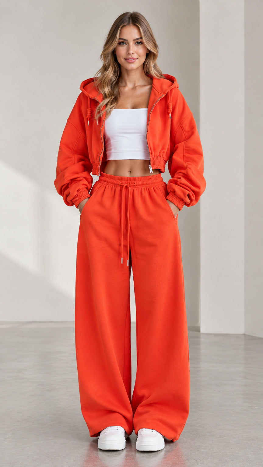 Front view of woman wearing orange cropped zip hoodie and matching wide leg sweatpants set