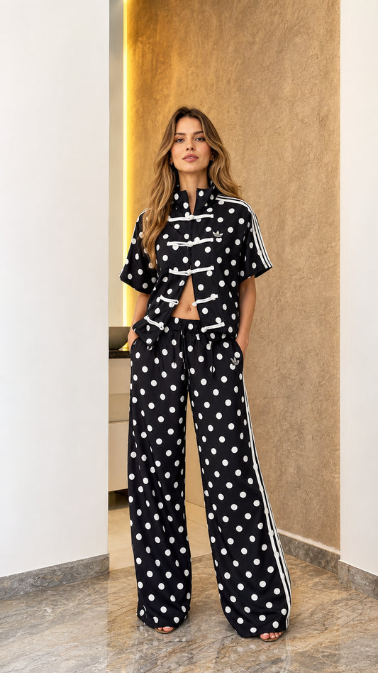 Model wearing black polka dot track jacket and wide-leg pants set, front view