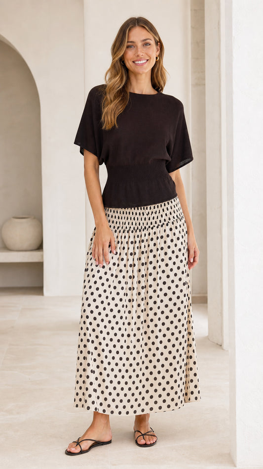 Front view of woman wearing black knit bodice and cream polka dot maxi dress