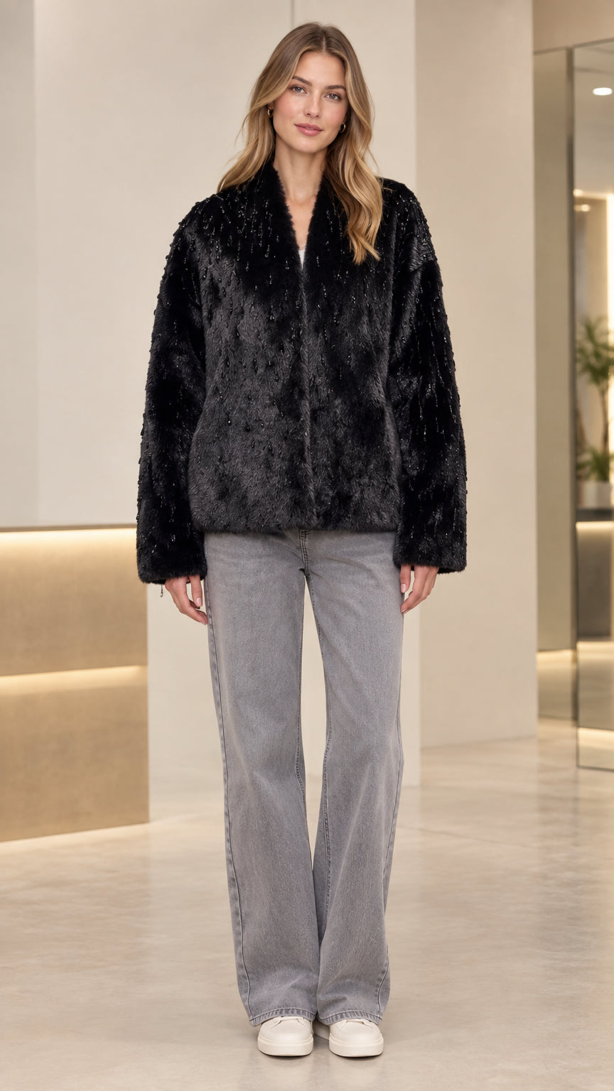 Front view of model wearing black beaded faux fur jacket with wide-leg denim