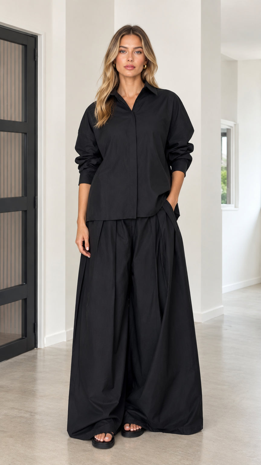 Front full view of women's relaxed two-piece set in black featuring collared shirt and wide-leg trousers