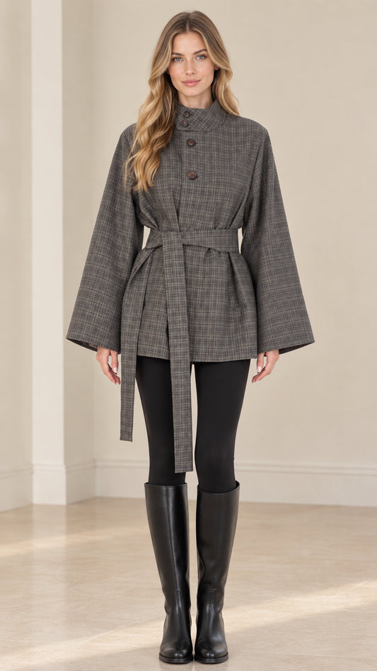 Front view of woman wearing grey plaid belted cape jacket with stand collar and wide sleeves
