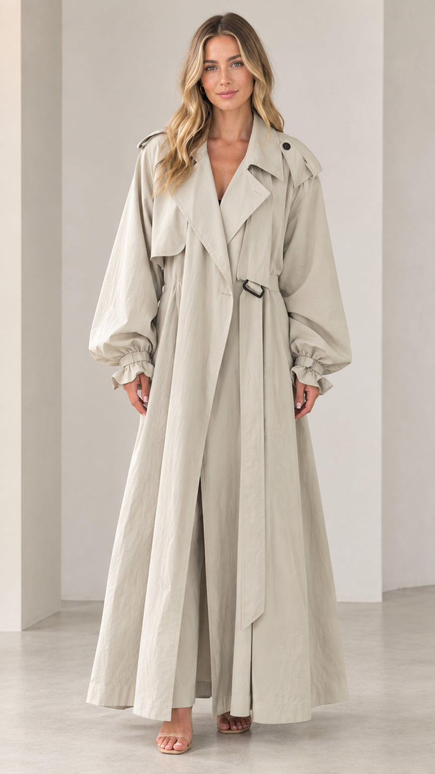 Full-length front view of woman wearing beige maxi trench coat with lantern sleeves and belt