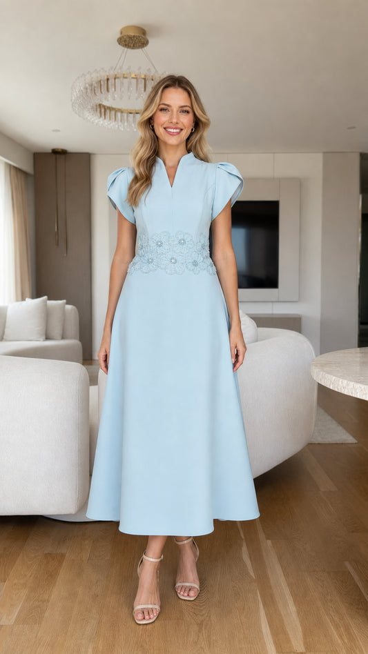 Front view of model wearing light blue A-line midi dress with beaded floral waist