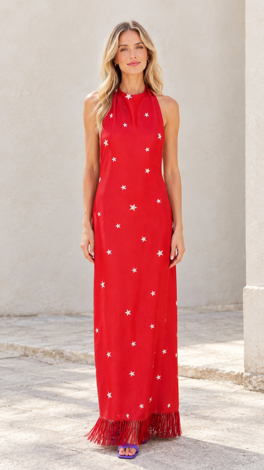 Front view of woman wearing red halter star print maxi dress with fringe hem