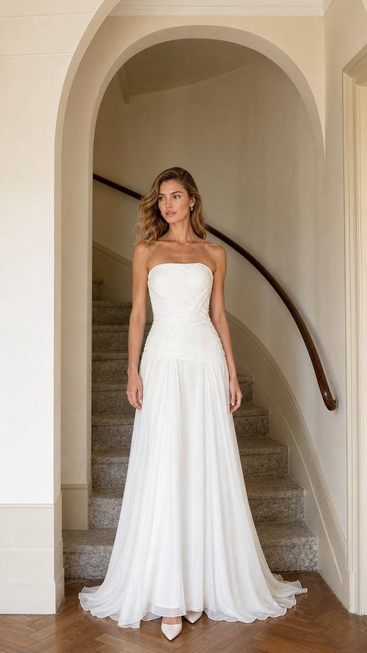 Front view of model wearing strapless white drop waist pleated chiffon maxi gown