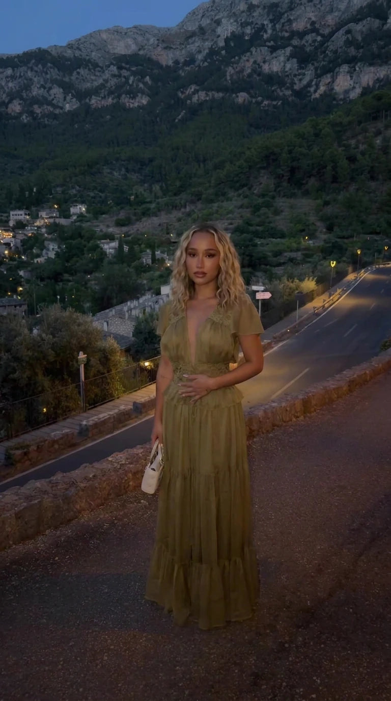 Front view of model wearing olive green tiered maxi dress with lace trim deep V-neck