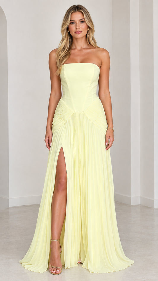 Front view of strapless light yellow pleated maxi gown with high slit