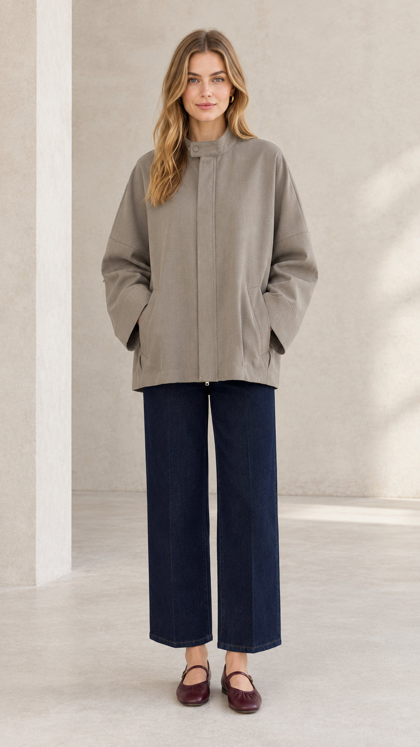 Front view of woman wearing taupe relaxed stand collar jacket with wide-leg navy pants