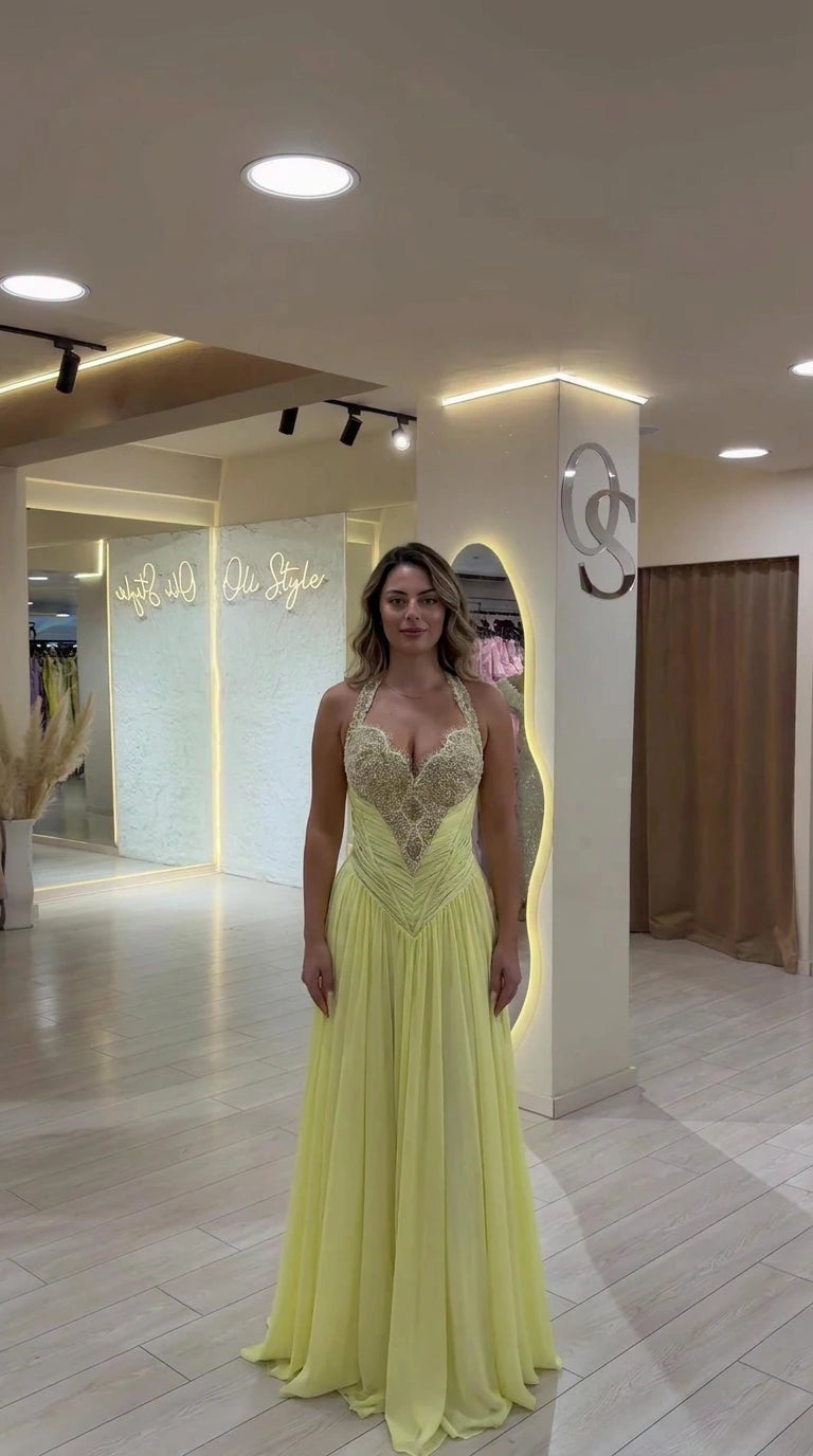 Front view of model wearing a light yellow halter embellished evening gown