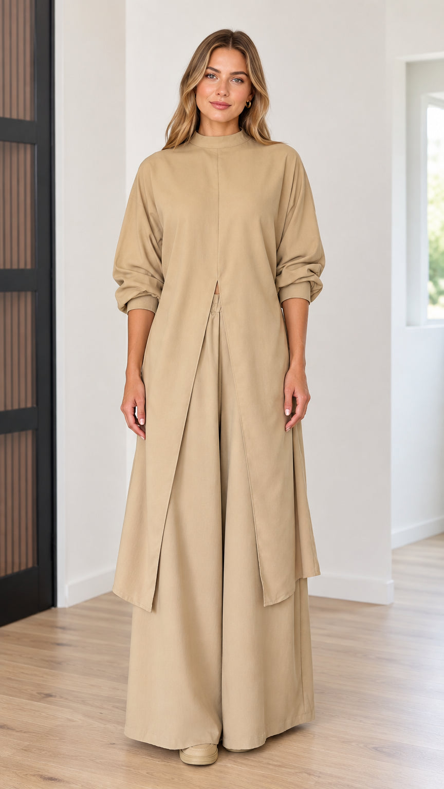 Front full-length view of model wearing beige longline mock neck slit tunic top and wide-leg pants set
