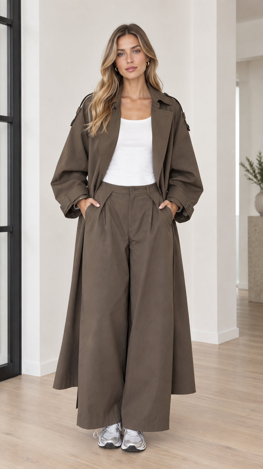Model wearing oversized olive brown maxi trench coat and matching wide-leg trousers front view