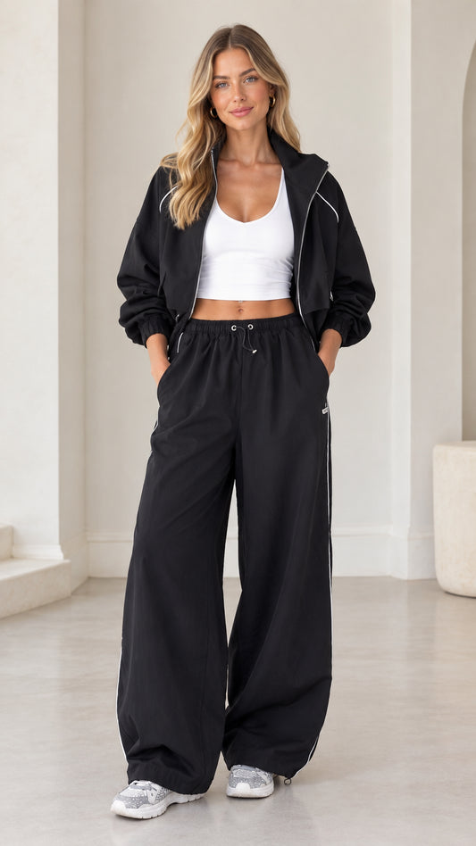 Full front view of model wearing black cropped zip-up tracksuit set with wide leg pants
