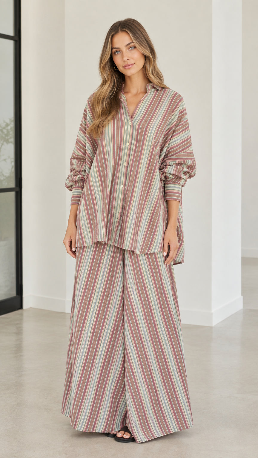 Full front view of model wearing rust multi-color striped oversized shirt and wide-leg pants set