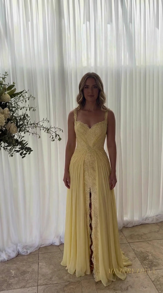 Front view of model wearing yellow sweetheart neck pleated chiffon evening gown with lace slit