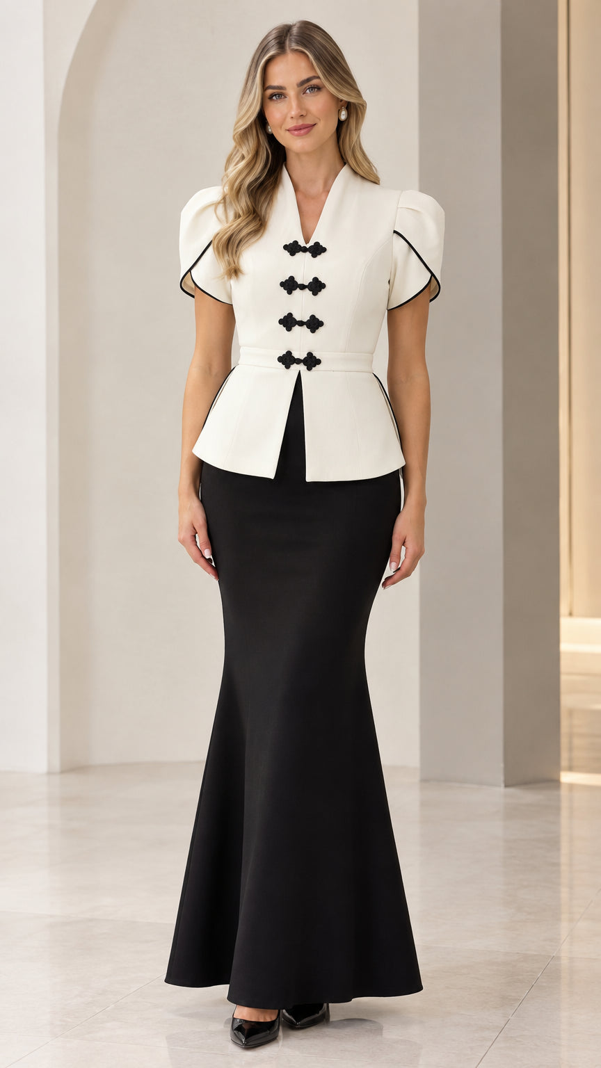 Front full-length view of woman wearing white peplum top with black trim and black mermaid maxi skirt