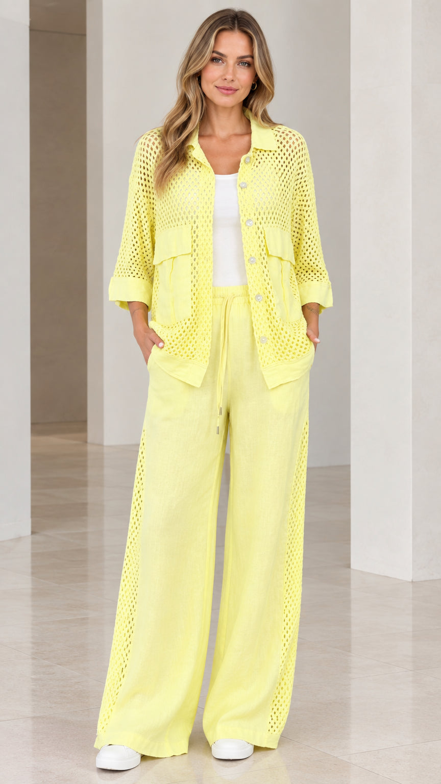 Full front view of woman wearing light yellow open knit button-down shirt and wide-leg pants set