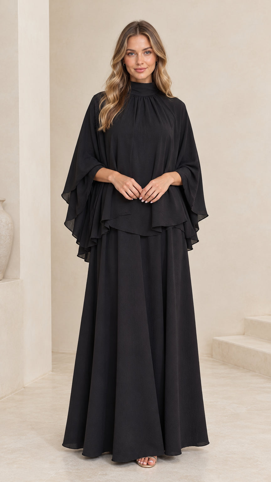 Front view of model wearing black mock neck cape overlay maxi dress