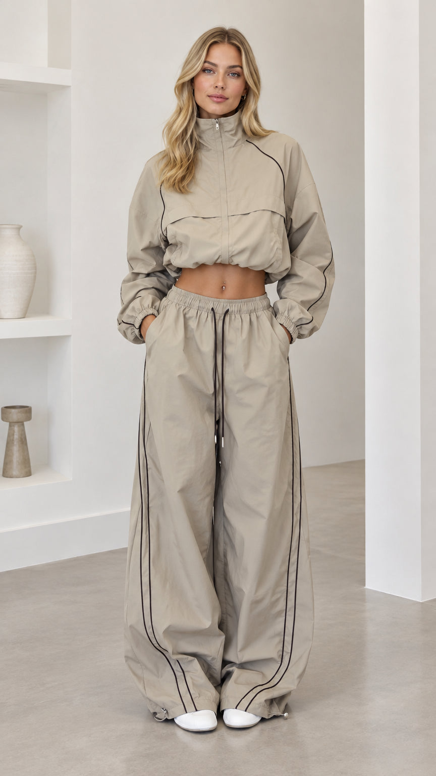 Front full-length view of model wearing taupe cropped windbreaker and wide-leg track pants set