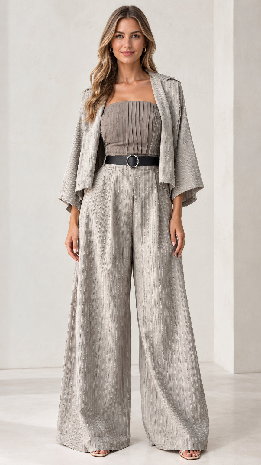 Front full-length view of woman wearing light grey pleated bandeau wide-leg jumpsuit with matching jacket and belt