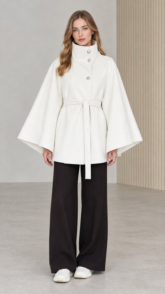 Front view of model wearing white high neck belted cape coat with black wide leg pants
