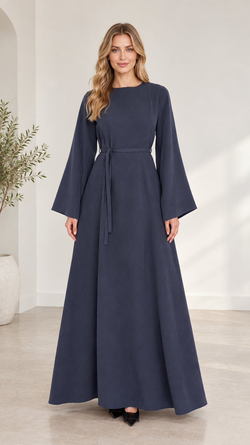 Full front view of woman wearing navy blue long bell sleeve modest maxi dress with waist tie