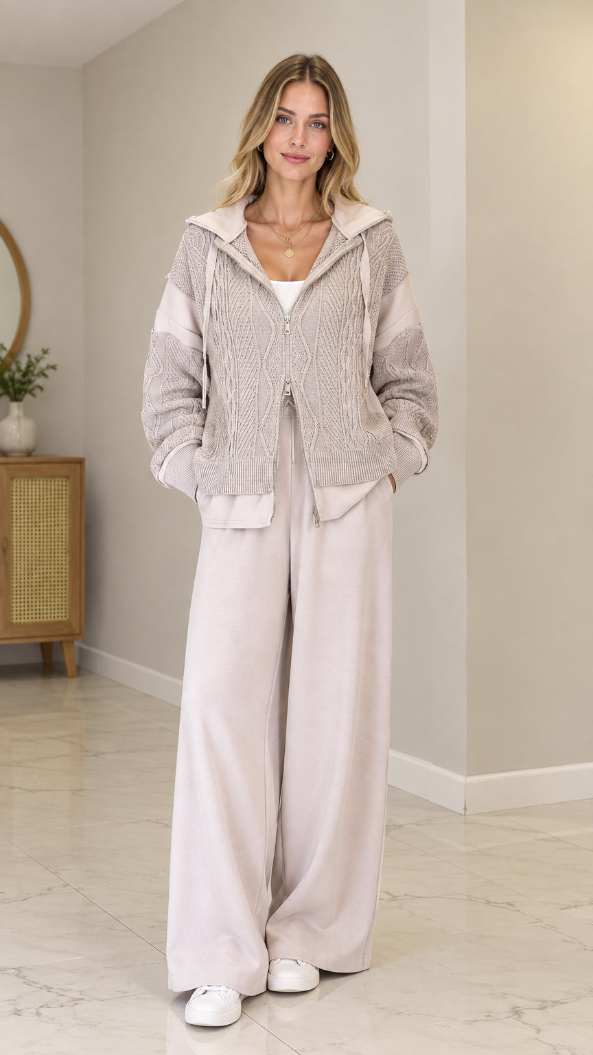Front full view of model wearing Oatmeal cable-knit zip-up hooded cardigan with wide-leg pants