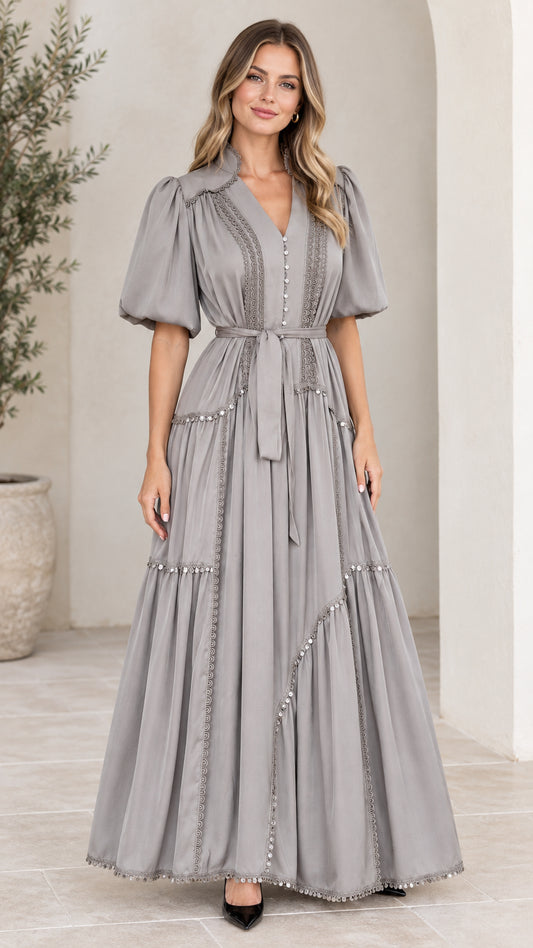Front full-length view of woman wearing grey tiered puff sleeve maxi dress with tie belt