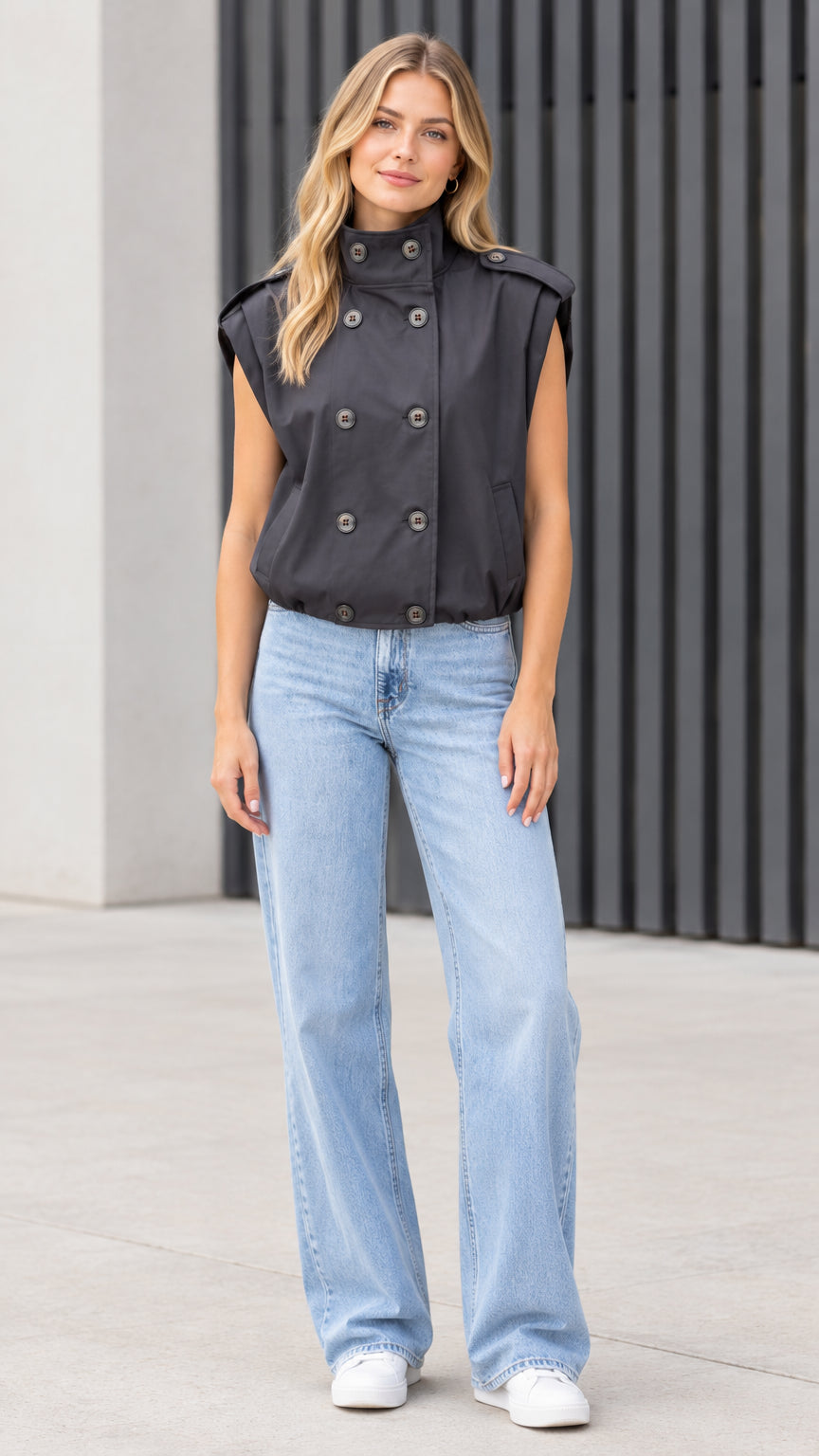 Front view of model wearing black double-breasted high-neck utility vest with light wash jeans