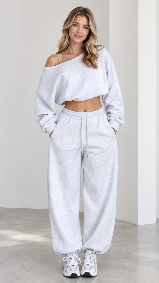 Front view of model wearing heather grey one-shoulder cropped sweatshirt and wide-leg sweatpants lounge set