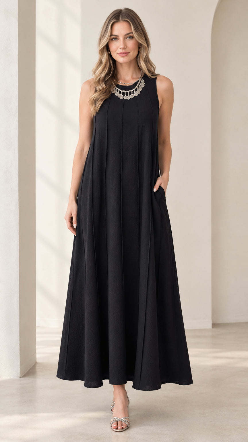 Front full-length view of woman wearing black sleeveless panel swing maxi dress with statement necklace