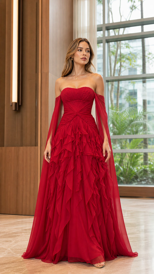 Model wearing red strapless ruched evening gown with cascading ruffles and cape sleeves front view