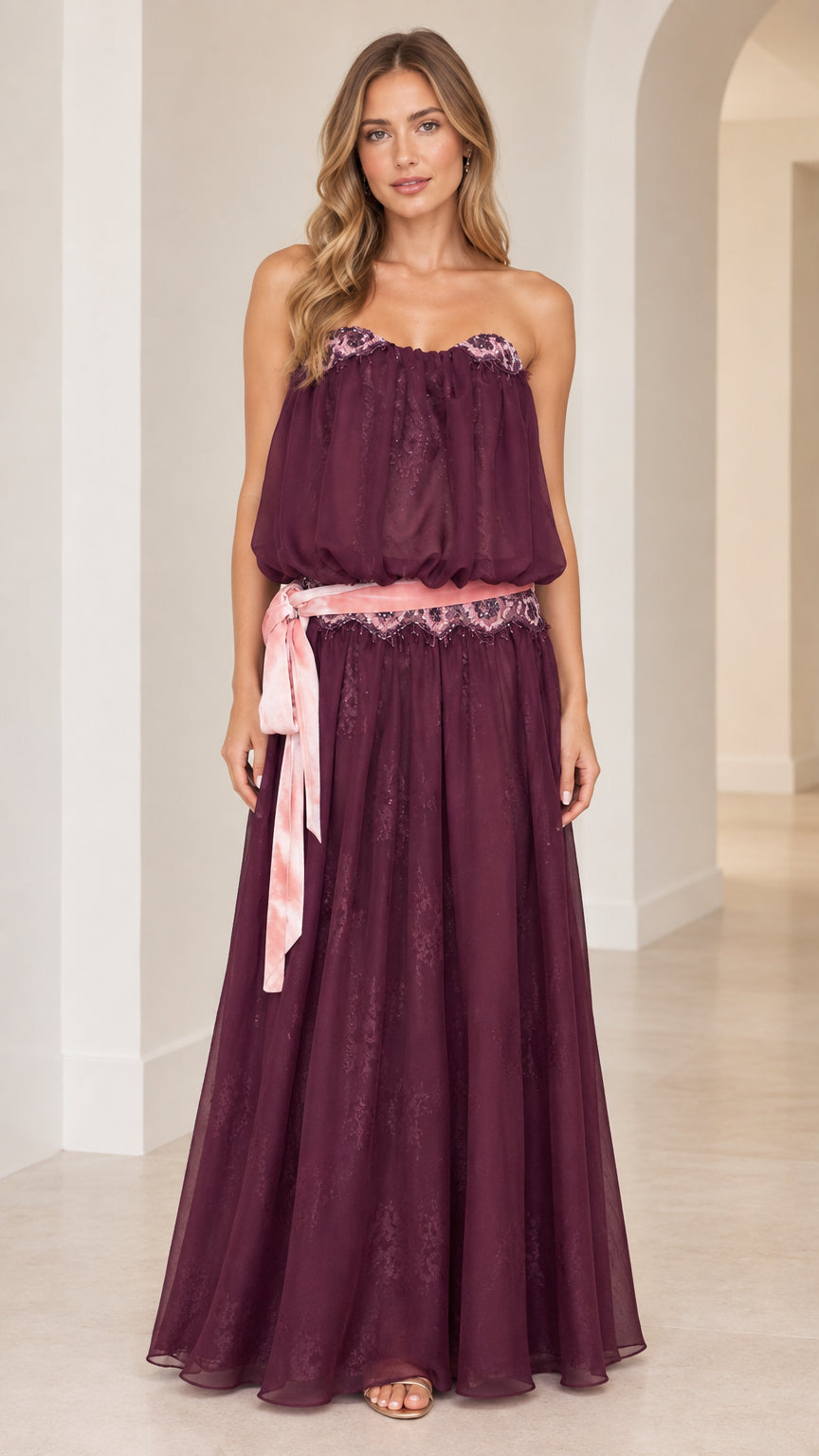 Front view of woman wearing strapless plum purple maxi dress with embroidered waist sash
