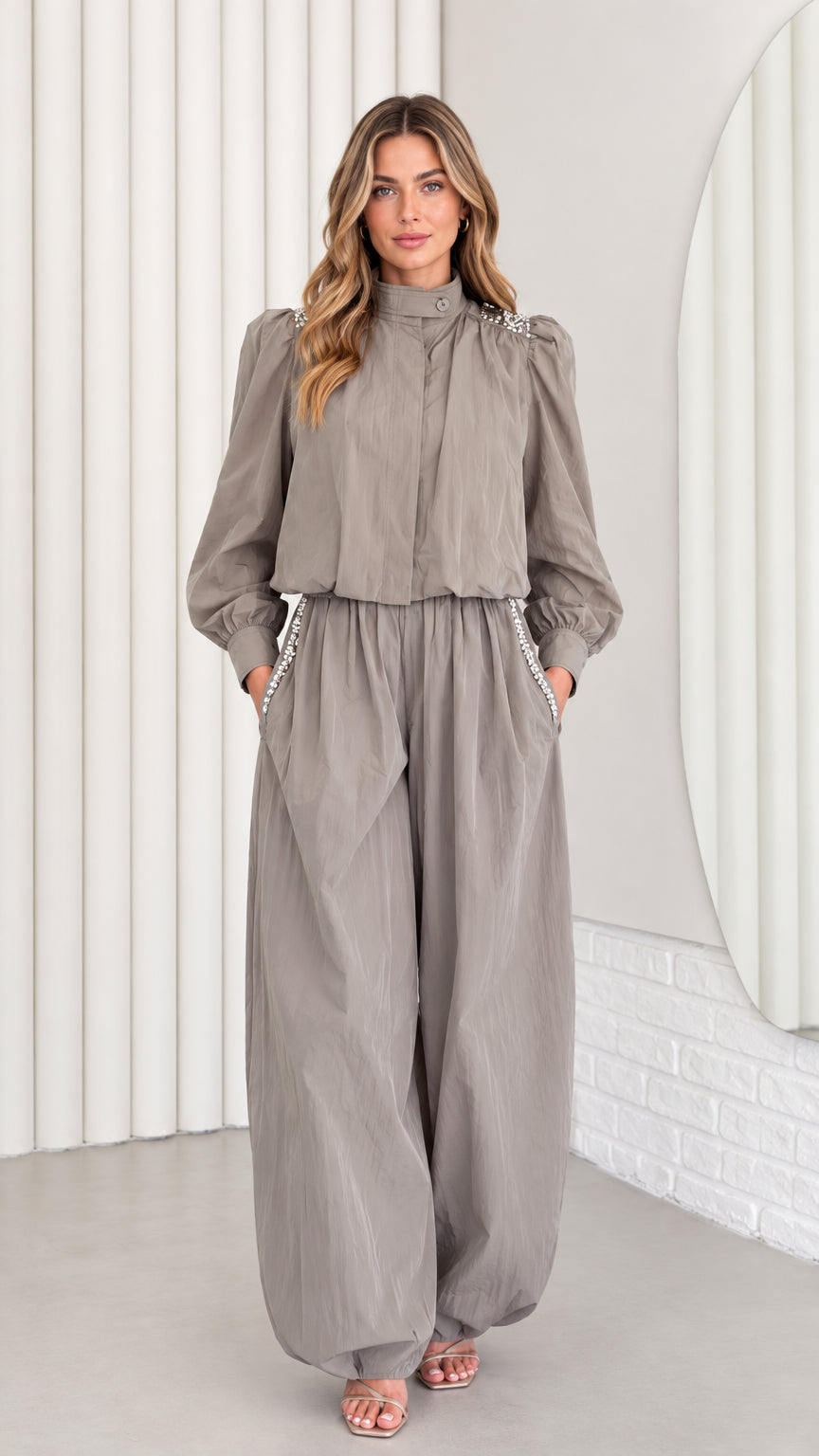 Front view of model wearing taupe grey rhinestone-embellished long sleeve jumpsuit