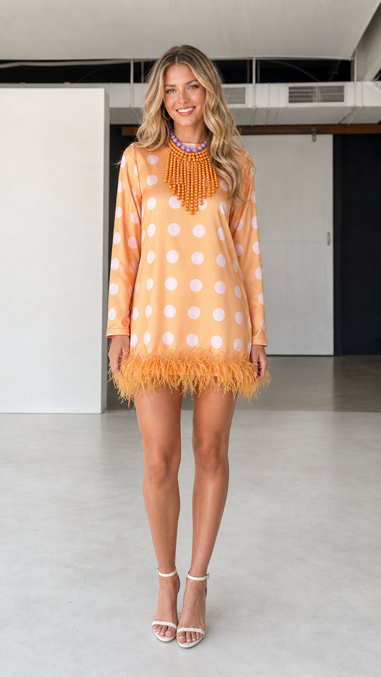 Front view of model wearing orange polka dot feather hem dress