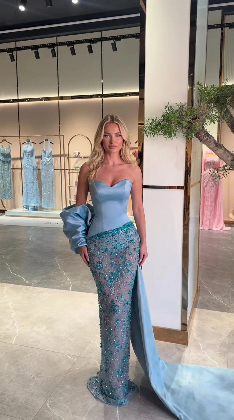 Front view of model wearing sky blue strapless beaded evening gown with bow train