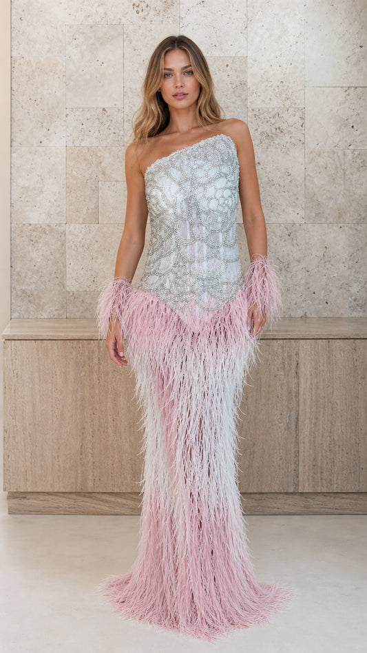 Front view of model wearing silver beaded one-shoulder gown with pink feather skirt